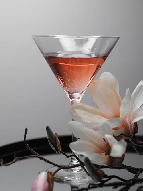 A pink cocktail with a magnolia flower on top