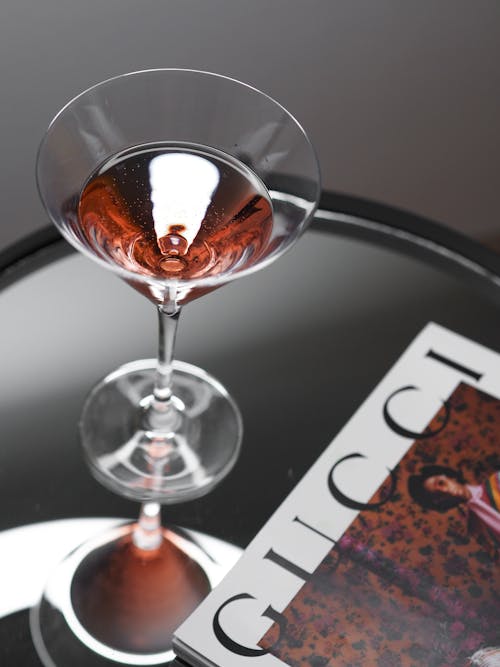 A glass of wine sits on top of a magazine