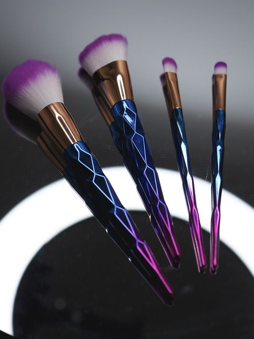 Free Colorful makeup brushes with geometric handles on a reflective surface, creating an artistic display. Stock Photo