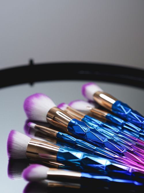 Free Colorful makeup brushes arranged on a sleek mirrored surface, perfect for beauty themes. Stock Photo