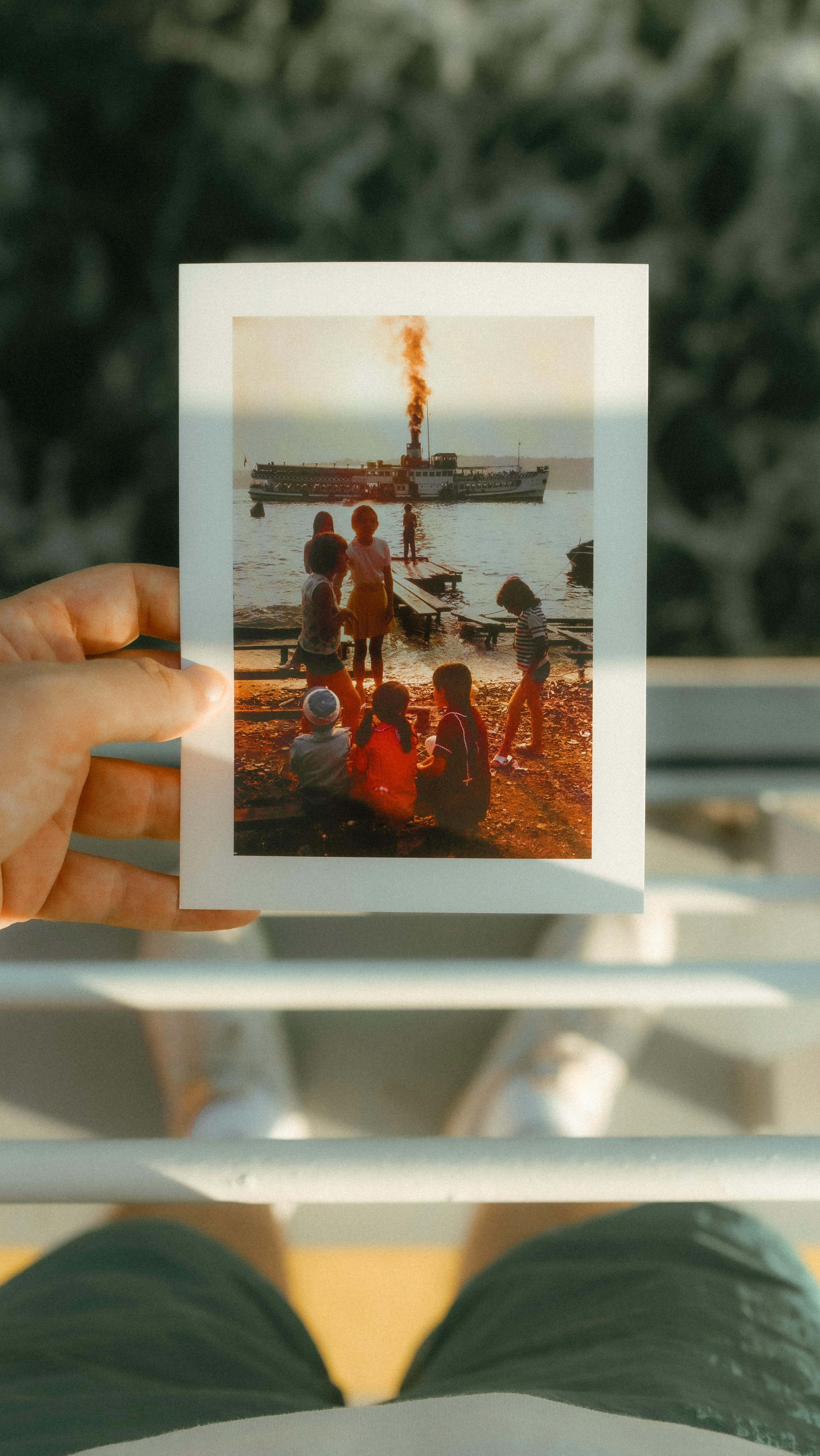A person holds a photo of a group near the sea with a ship in Istanbul.