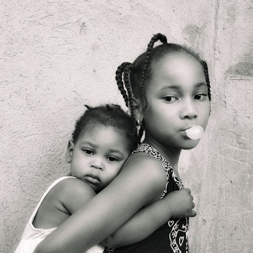 Free Two young girls are holding each other and one is chewing gum Stock Photo