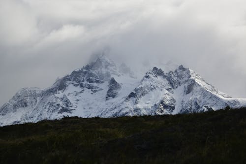 A snowy mountain with clouds in the sky