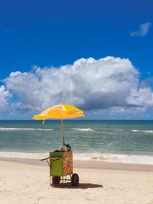 A cart on the beach with an umbrella and a beach chair
