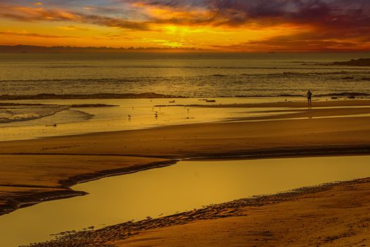 A serene beach scene at sunset with glowing colors and gentle waves reflecting the evening light.