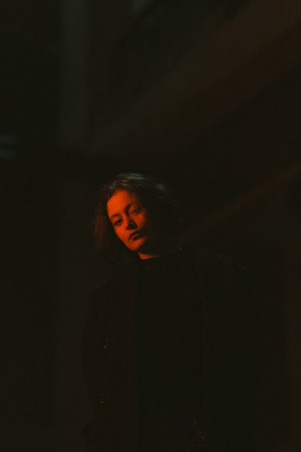 Woman under a shaft of red light in a dark room, photo by Fakhri Baghirov on Pexels