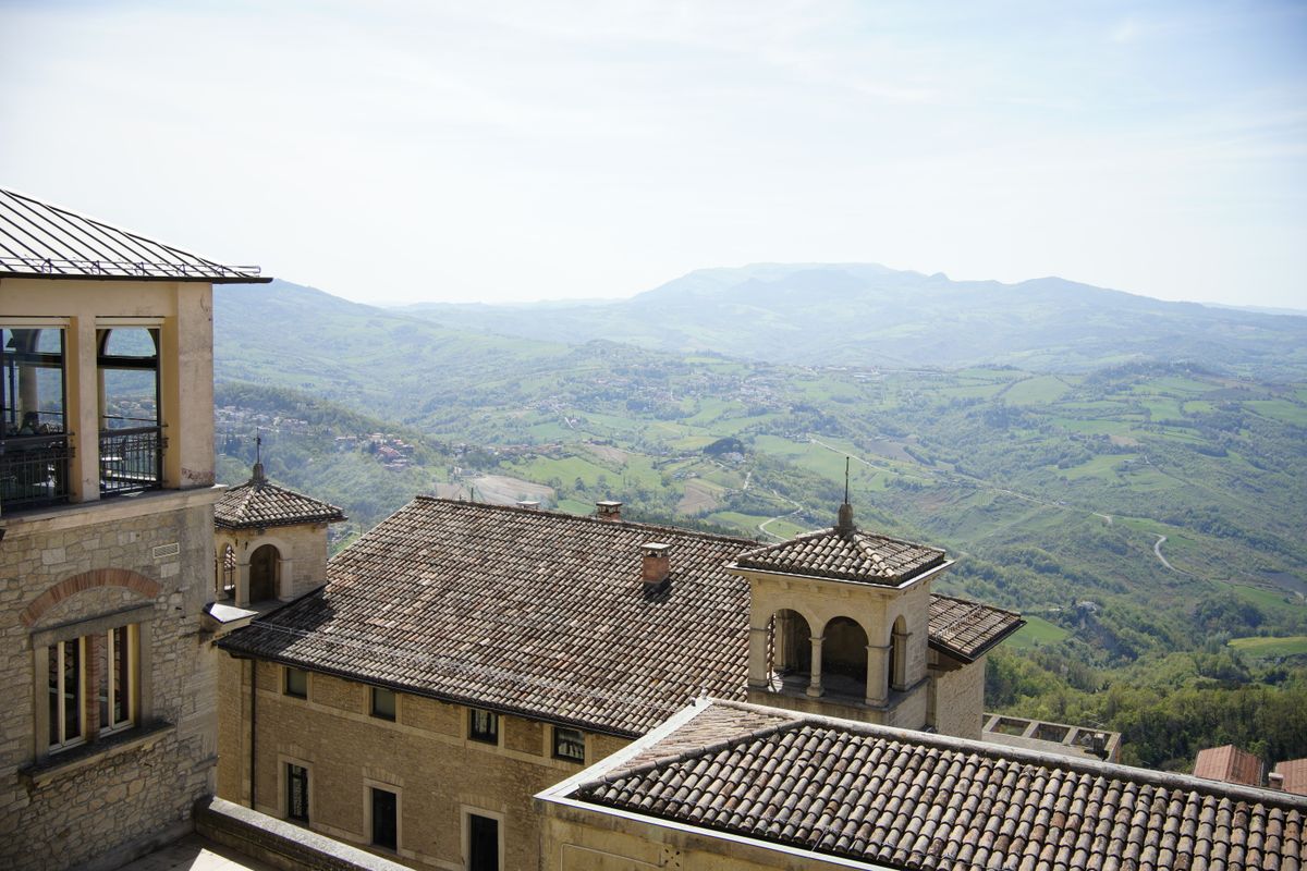 Acoperișurile de olane ale centrului istoric din San Marino, cu dealurile verzi în fundal
