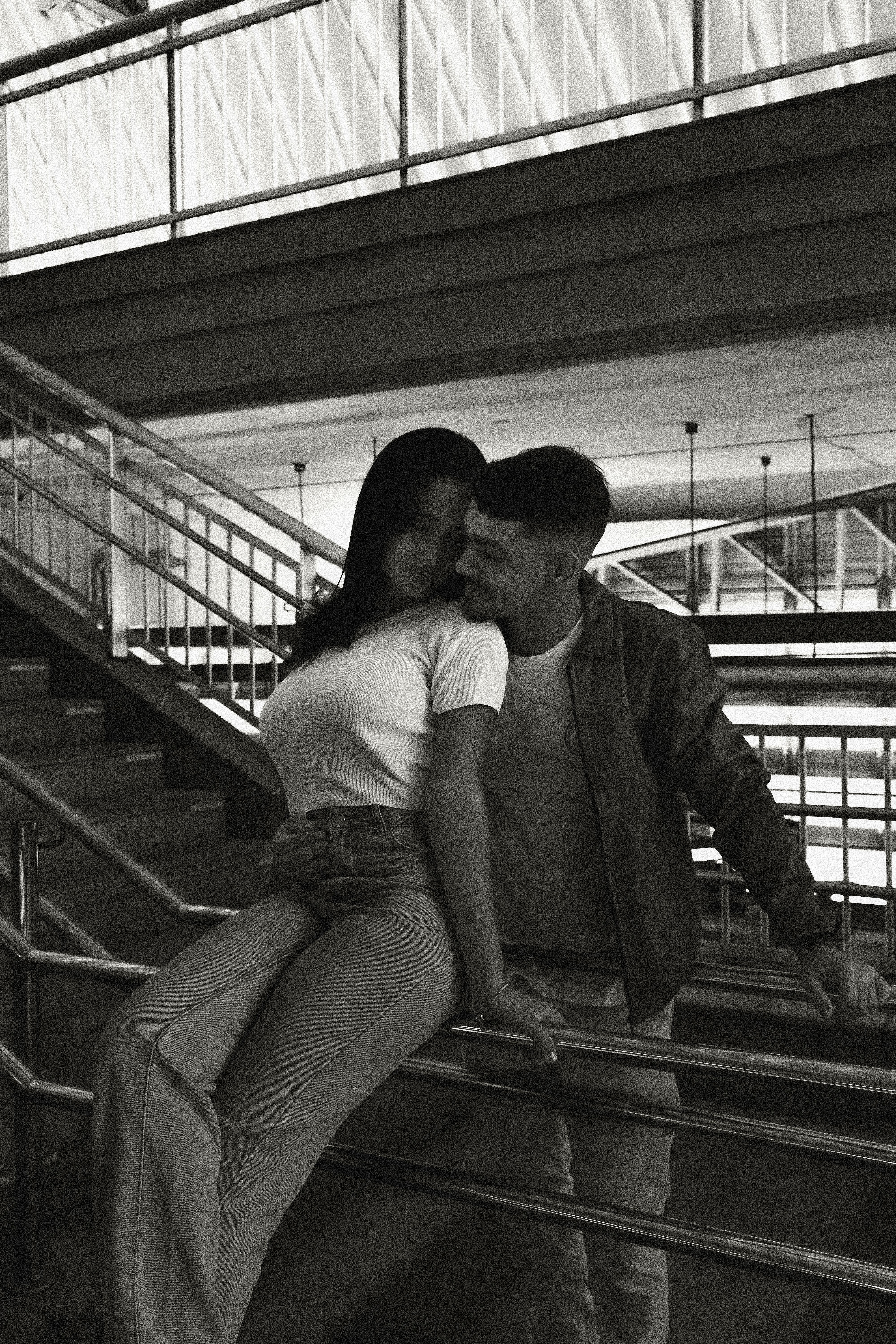 Romantic couple embraced on a staircase in urban setting, black and white.