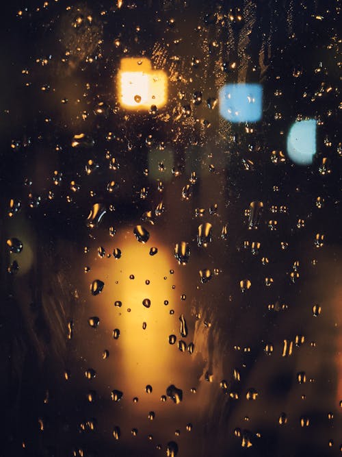 Rain drops on a window with lights in the background