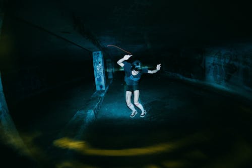 A person skateboarding in a dark tunnel