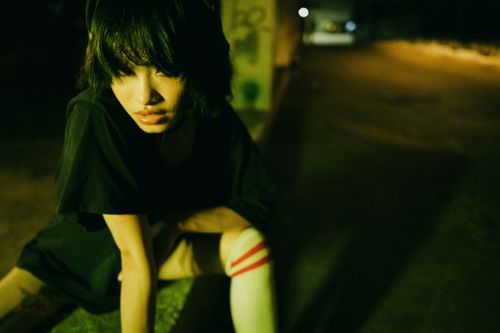 Free A moody, dimly lit portrait of a young woman at night with a dramatic pose. Stock Photo