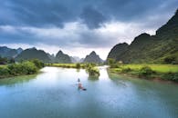 戏剧性的天空下，河流的宁静景色与郁郁葱葱的青山相映成趣