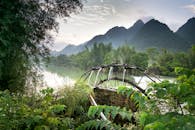 郁郁葱葱的绿色山脉间，美丽的河流景观中点缀着传统的水车