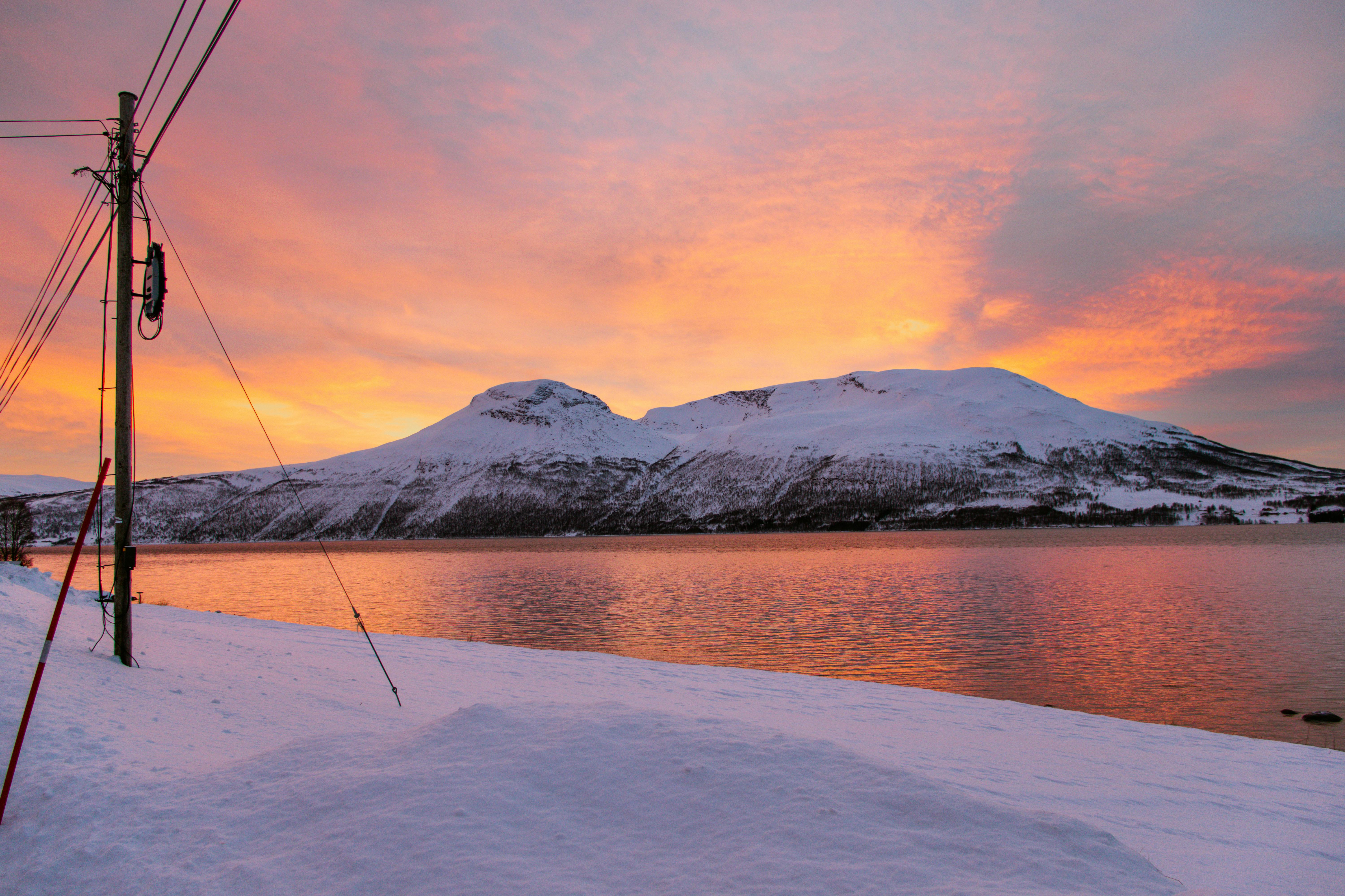 Captivating view of a snowy mountain and lake at sunset in Laksvatn, Norway.