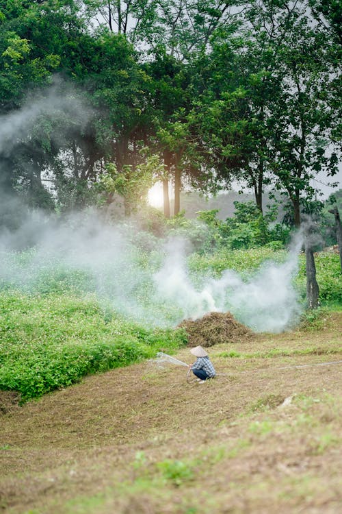 A man is spraying smoke from a fire in the grass