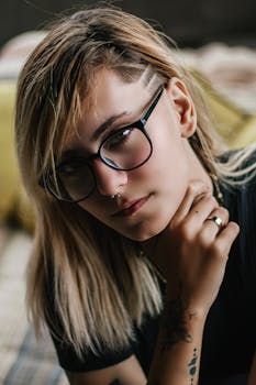 一位戴眼镜、有纹身的体贴女人的特写肖像，展现了她独特的风格与表情