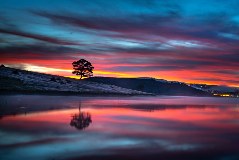 Stunning sunset over a tranquil lake with vibrant colors and a scenic landscape reflection.
