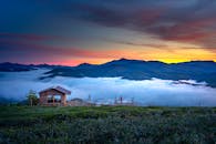 日出时分，乡村房屋与雾蒙蒙的山脉构成壮丽景色，营造出宁静的乡村氛围