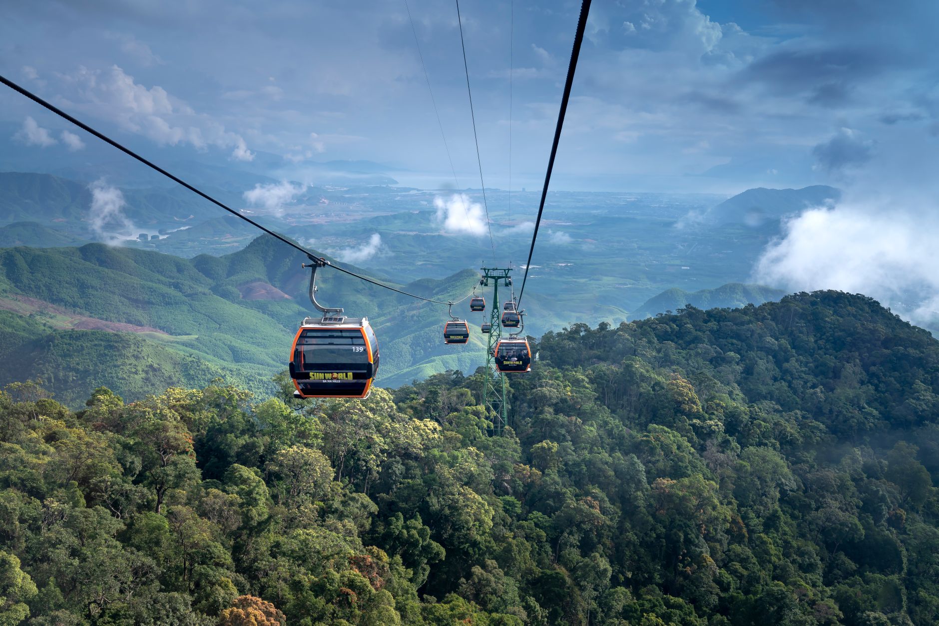 Experience breathtaking views from a cable car ride over lush, foggy mountains, perfect for an adventurous journey.