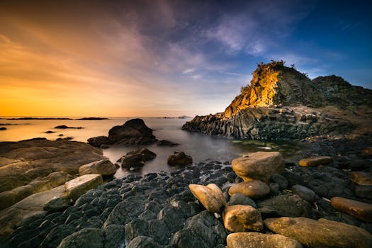 日落时分，戏剧性的海滨景观与岩石海岸，捕捉到了充满活力的色彩和宁静的水面倒影