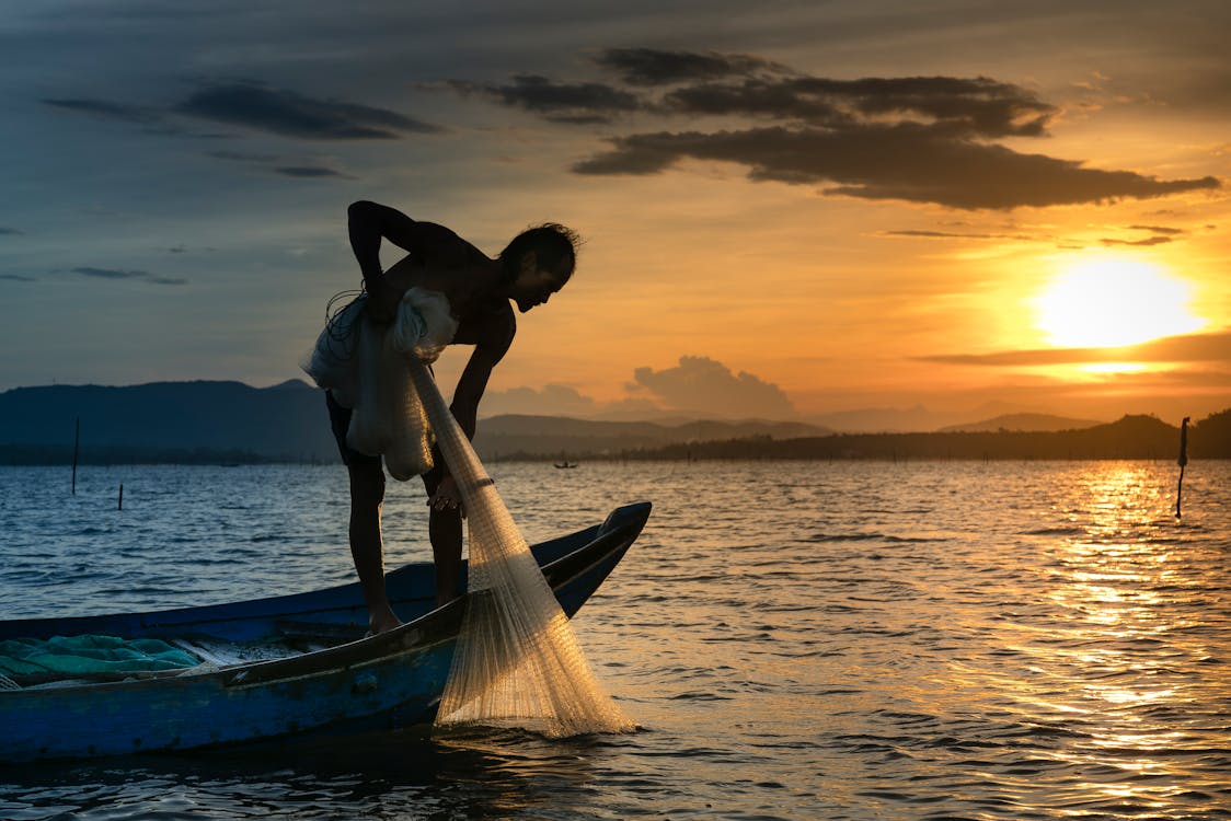 Free Man on Boat Holding White Mesh Fishing Net Stock Photo