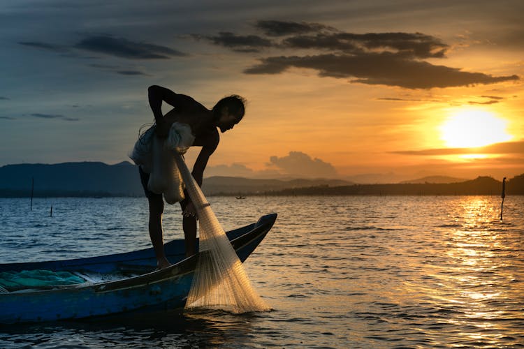 Man On Boat Holding White Mesh Fishing Net