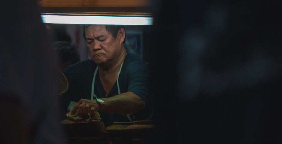 A vendor working a grill at a night market in Petaling Jaya — treatment is scheduled around trading, not instead of it