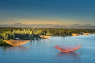 日出时分，宁静的湖面被树木和山脉环绕，渔网点缀其间