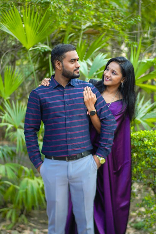 A man and woman posing for a photo in front of trees