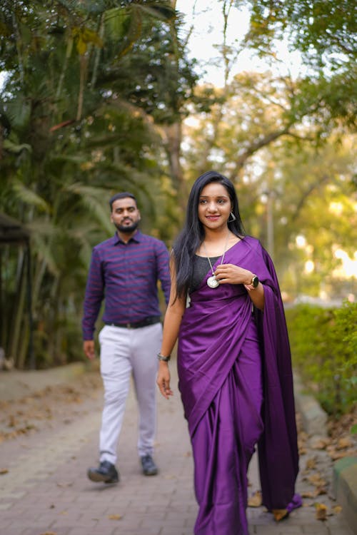 A man and woman in purple sari walking down a path