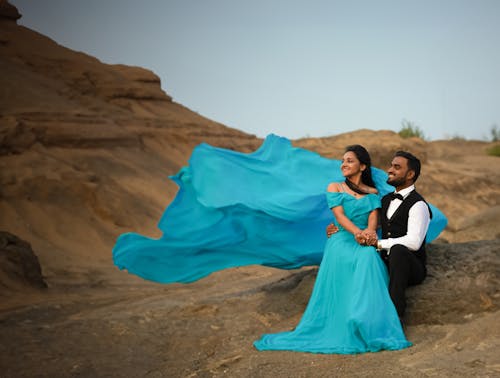 A couple in blue dress sitting on rocks