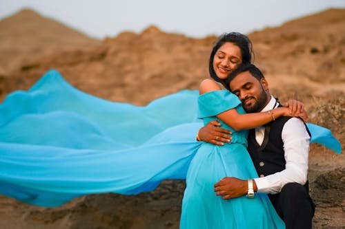 A couple in blue dress pose for a photo