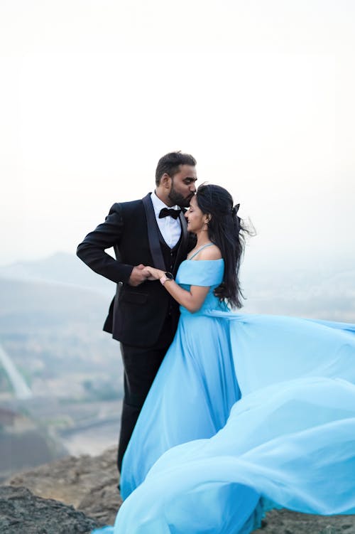 A couple in blue gowns standing on a cliff