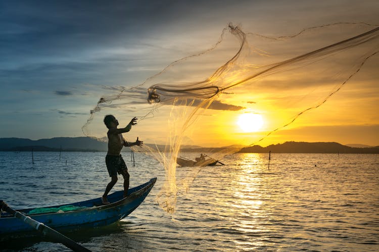 Fisherman Throwing Fish Net On Lake