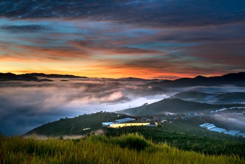 Free Breathtaking sunrise with mist covering a lush mountainous landscape, creating a serene atmosphere. Stock Photo