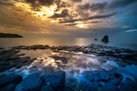 令人惊叹的日落，引人注目的云层反射在岩石海岸和宁静的大海上