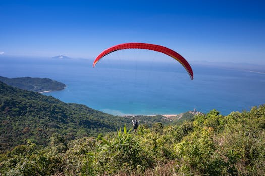 滑翔伞翱翔在郁郁葱葱的绿植与蔚蓝大海构成的沿海景观之上