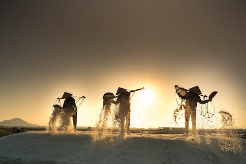 Three People Carrying Poles