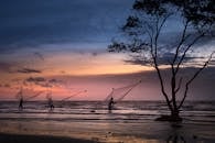 渔民在海边撒网，映衬着充满活力的日落