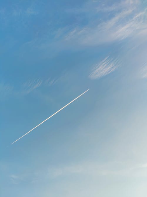 A plane flying through the sky with a contrail