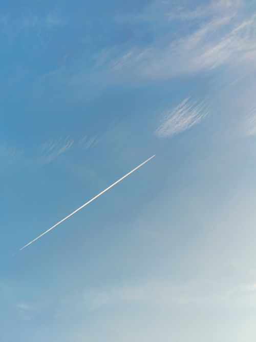 Free A sleek airplane contrail against a clear blue sky captured in a vertical shot. Stock Photo