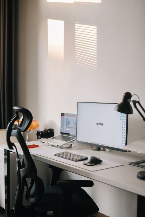 Estação de trabalho minimalista com monitor, cadeira e acessórios organizados