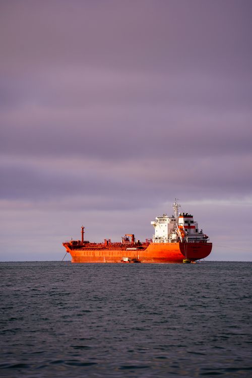 Free A vibrant red cargo ship sailing under a dramatic purple sky in Samsun, Türkiye. Stock Photo