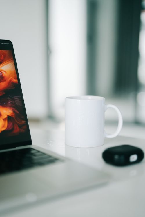 Free Close-up view of a modern desk setup with a laptop and coffee mug, ideal for work from home inspiration. Stock Photo