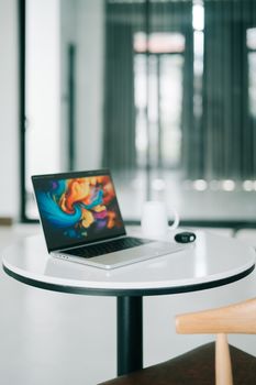 Sleek laptop on a minimalist round table in a contemporary office setting.