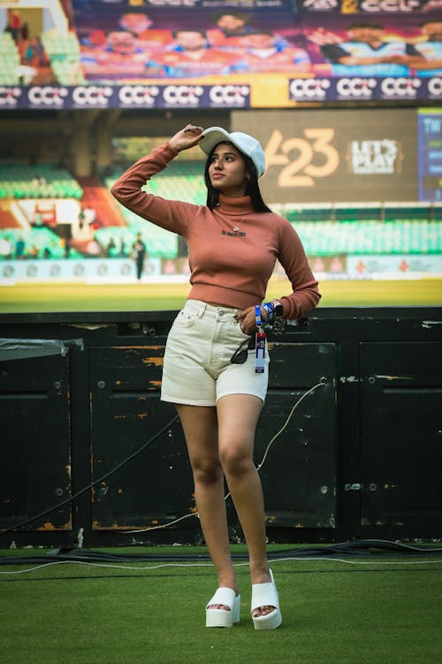 A woman in shorts and a top standing on a field