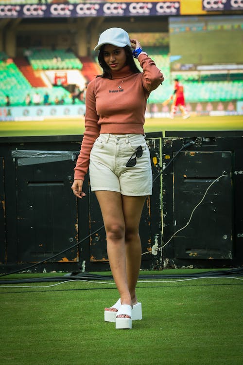 A woman in white shorts and a pink top walking on the field