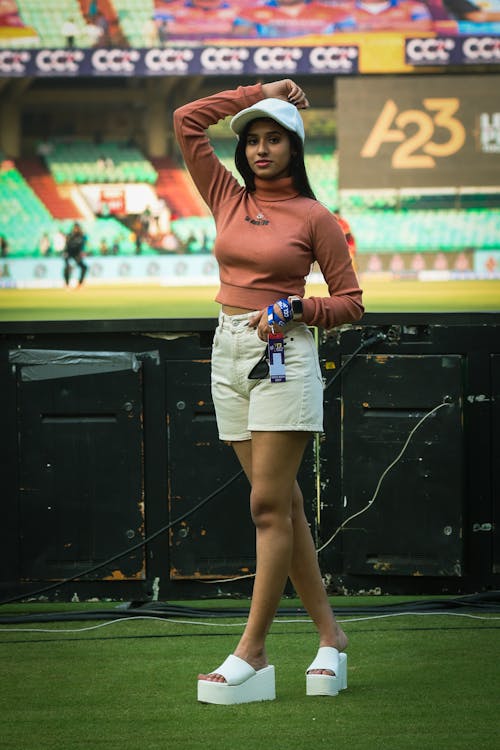 A woman in shorts and a top standing on the field