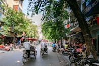 阳光明媚的日子里，一条热闹的城市街道上，人们骑着自行车，市场活动熙熙攘攘