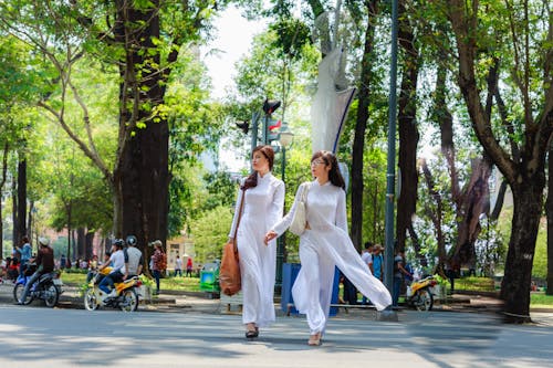 穿白色衣服的兩個女人在過馬路時手牽著手的照片